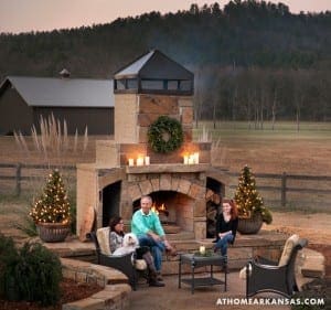 Stone outdoor fireplace with seating and Christmas trees.