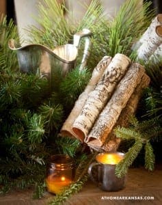 Silver pitcher, birch logs, and evergreen branches with candles.