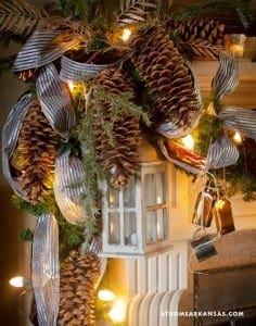 Decorated mantel with pinecones, silver ribbon, and a miniature window.