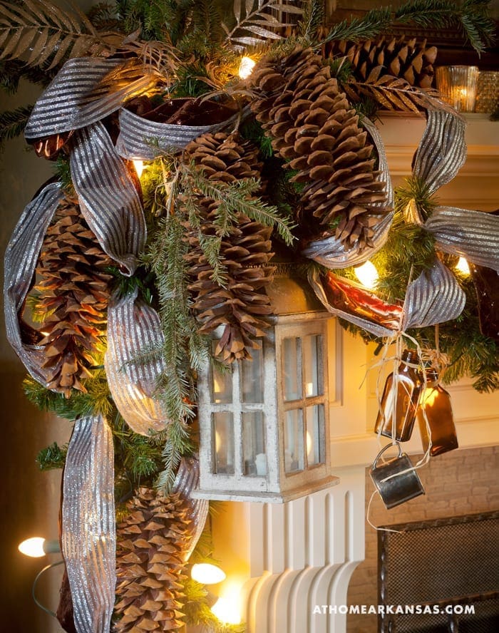 Decorated mantel with pinecones, silver ribbon, and a miniature window.