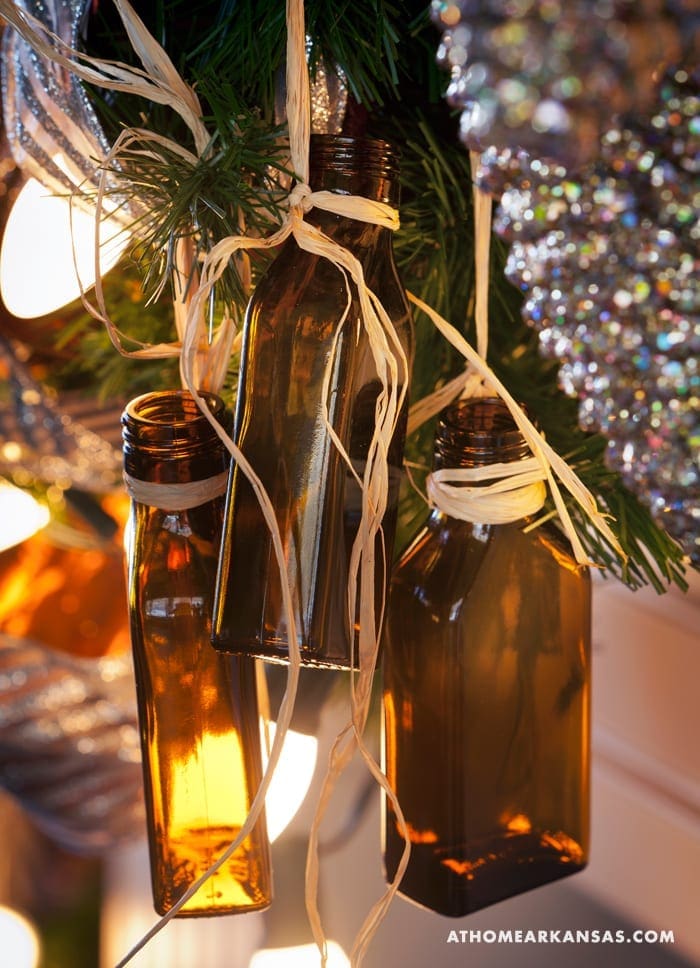 Brown bottles with twine hanging from a Christmas tree.