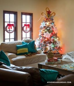 Cream sofa with teal pillows, Christmas tree, and coffee table.