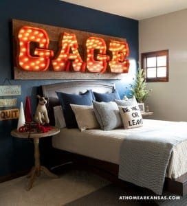 Bedroom with a large, illuminated ‘GAGE’ sign and blue walls.