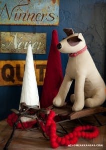 Tan dog toy with red collar on wooden sled.