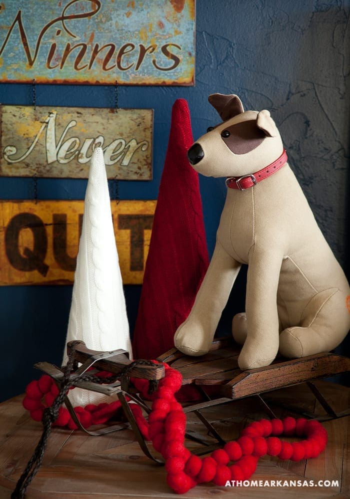 Tan dog toy with red collar on wooden sled.