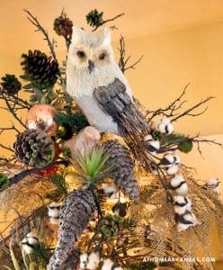 White owl ornament with pinecones, berries, and branches.
