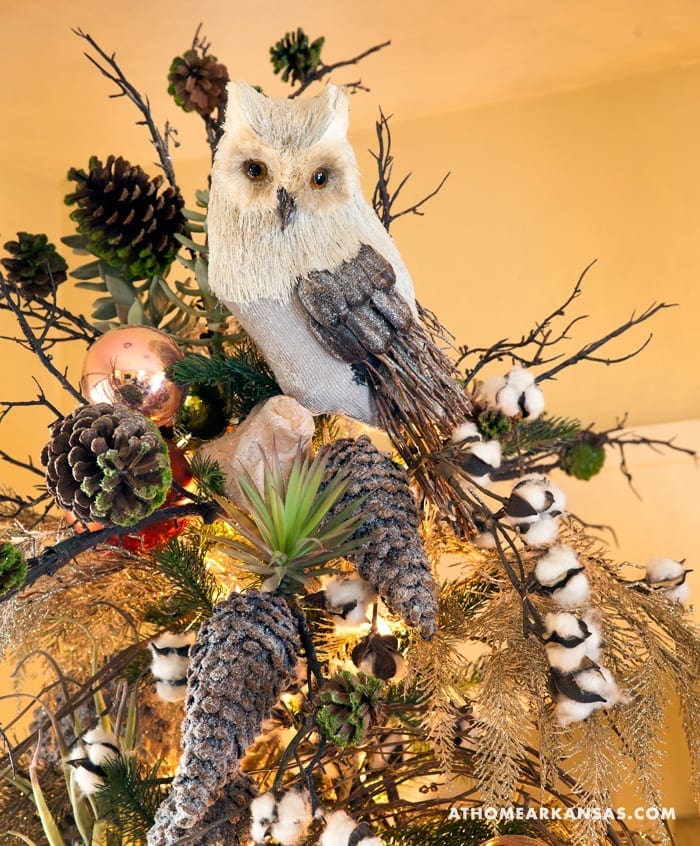 White owl ornament with pinecones, berries, and branches.