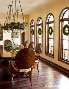 Dining room with arched windows, wooden floors, and a chandelier.