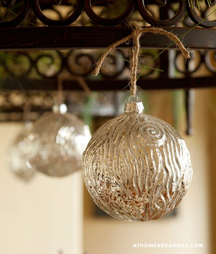 Silver glass ornaments hanging from a jute ball.
