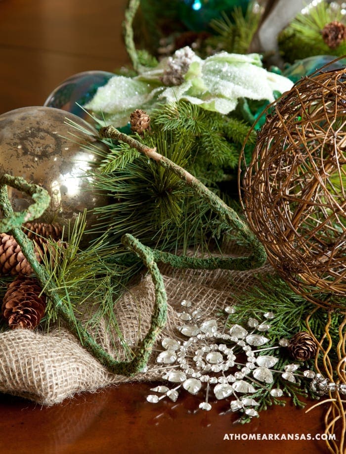 Close-up of decorative winter arrangement with ornaments, pine, and burlap.