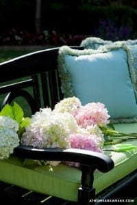 Black wrought iron bench with hydrangea and pillows.