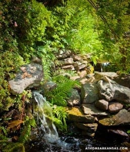 Stone waterfall and ferns in a shaded garden.