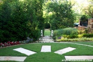 Stone staircase leading through a lush green garden with statues.
