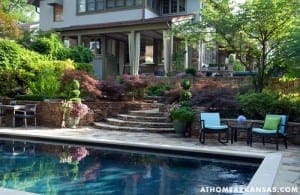 Stone patio, pool, and outdoor seating area with landscaping.