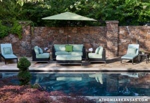 Stone wall, outdoor seating area, and pool in landscape.