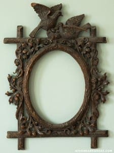 Ornate, dark wood frame with bird carving on a pale green wall.
