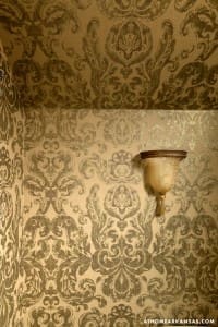 Gold dam repeat wallpaper with a wall-mounted sconce.