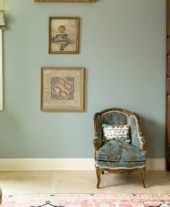 Gray wall with framed artwork and upholstered armchair.