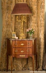 Dark wood nightstand with lamp and floral arrangement.