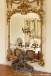 Ornate gold-framed mirror reflects a dining room.