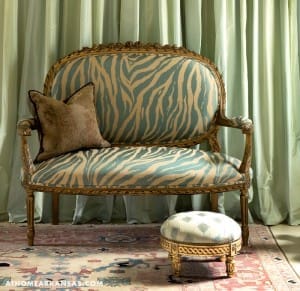 Gold and turquoise striped sofa with a velvet pillow.