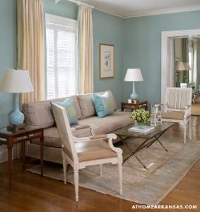 Light-blue sofa in a light-blue room with beige rug and wooden floors.