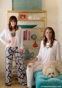 Two women with a dog pose in a living room.