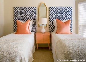 Blue and white patterned headboard with two orange pillows, bedside table.