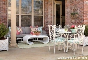 Brick porch with outdoor seating, table, and floral accents.