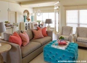 Cream-colored living room with gray sofa, patterned armchairs, and a turquoise ottoman.