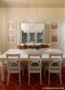 White dining table with gray chairs and floral centerpiece.