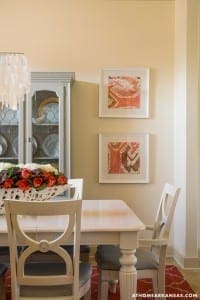 White dining table with gray chairs, artwork, and a light fixture.