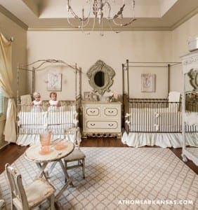 Cream-colored bedroom with iron cribs and a patterned rug.