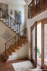 Wooden staircase with wrought iron railing and artwork.