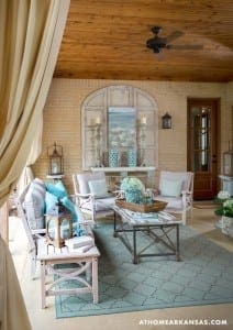 Covered porch with brick walls, wooden ceiling, and seating area.