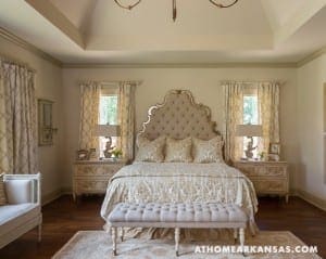 Master bedroom with a tufted headboard, drapes, and antique furniture.