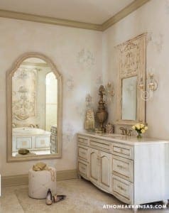 White vanity with ornate mirror and floral wall decor.