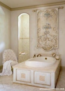 White bathtub with gold fixtures and a decorative wall panel.