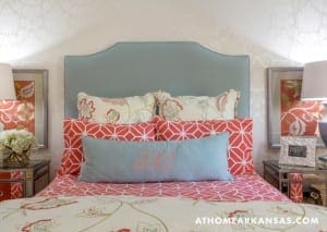 Bedroom with teal headboard, patterned pillows, and framed artwork.