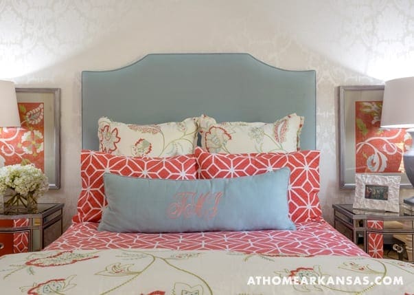 Bedroom with teal headboard, patterned pillows, and framed artwork.