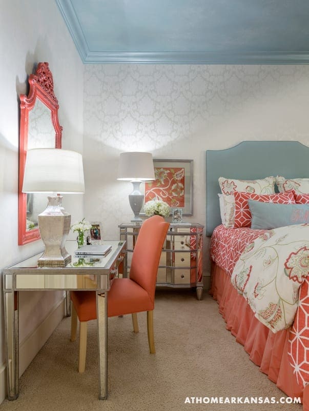 Blue and white bedroom with patterned wallpaper, headboard, and mirrored furniture.