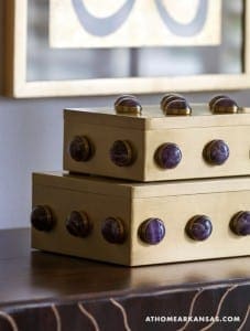 Brass boxes with amethyst stones, stacked on a reflective surface.