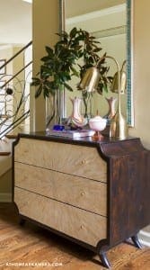 Dark wood dresser with patterned wallpaper and a mirror.
