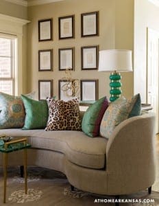 Curved sofa with patterned pillows and framed artwork.