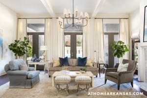 Large living room with neutral furniture, curtains, and a chandelier.