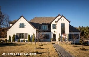 White, two-story house with gabled roof and stone walkway.