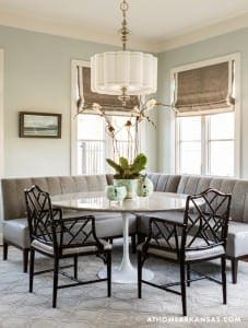 Gray breakfast nook with a banquette, chandelier, and patterned rug.