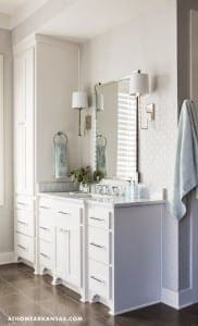 White bathroom vanity with mirror, sconces, and towel.