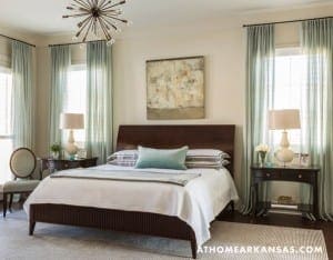 Bedroom with a dark wood bed, teal curtains, and a large starburst chandelier.