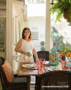 Woman in white dress stands beside outdoor table with orange accents.